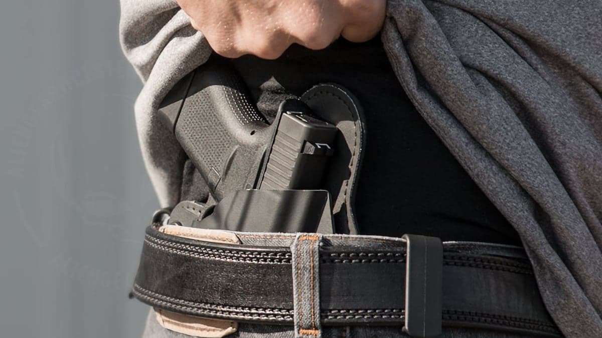 Person lifting shirt to reveal a concealed handgun in a waistband holster